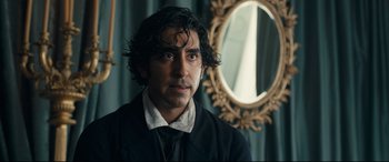 Movie still from “The Personal History of David Copperfield” (2019), directed by Armando Iannucci – A man with long black hair standing in front of a mirror; Close Up shot, Over the shoulder angle
