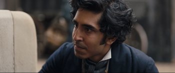 Movie still from “The Personal History of David Copperfield” (2019), directed by Armando Iannucci – A person wearing a suit and tie; Close Up shot, Over the shoulder angle