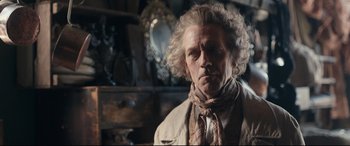 Movie still from “The Personal History of David Copperfield” (2019), directed by Armando Iannucci – A person wearing a suit and tie; Close Up shot, Over the shoulder angle