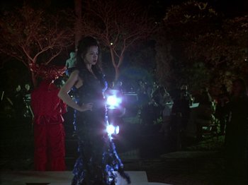 A woman in a black dress is standing in the dark