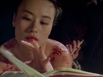 Movie still from “The Pillow Book” (1995), directed by Peter Greenaway – A woman is reading a book while holding a pencil; Close Up shot, High angle
