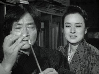 Movie still from “The Pillow Book” (1995), directed by Peter Greenaway – An older man and a younger woman are posing for a picture; Close Up shot, Low angle
