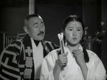 Movie still from “The Pillow Book” (1995), directed by Peter Greenaway – An older man standing next to a young woman; Close Up shot, Low angle
