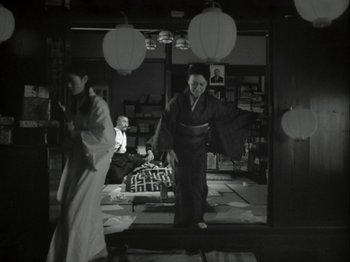 Movie still from “The Pillow Book” (1995), directed by Peter Greenaway – A woman in a kimono standing in front of a window; Wide shot, Low angle