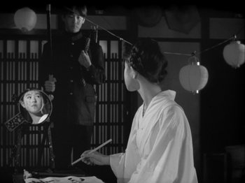 Movie still from “The Pillow Book” (1995), directed by Peter Greenaway – A woman is holding a brush in front of a mirror; Medium shot, Over the shoulder angle
