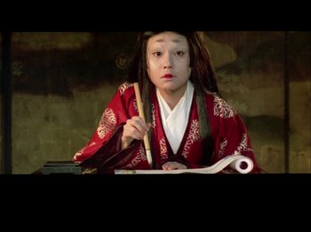 Movie still from “The Pillow Book” (1995), directed by Peter Greenaway – A person with long hair holding a chopstick; Close Up shot, High angle