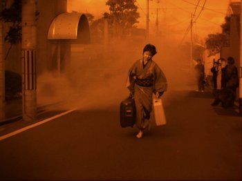 Movie still from “The Pillow Book” (1995), directed by Peter Greenaway – A woman walking down a street holding luggage; Wide shot, High angle