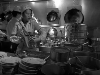 Movie still from “The Pillow Book” (1995), directed by Peter Greenaway – A woman in a kitchen preparing food in a restaurant; Medium shot, High angle