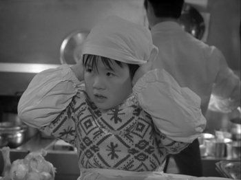 Movie still from “The Pillow Book” (1995), directed by Peter Greenaway – A little girl wearing a white hat in a black and white photo; Close Up shot, High angle