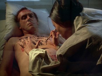 Movie still from “The Pillow Book” (1995), directed by Peter Greenaway – A woman is tattooing a man's chest in a hospital bed; Close Up shot, Overhead angle