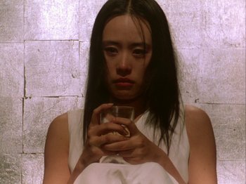 Movie still from “The Pillow Book” (1995), directed by Peter Greenaway – A young woman holding a glass of water; Close Up shot, Low angle