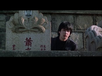 Movie still from “The Pillow Book” (1995), directed by Peter Greenaway – A man standing in front of a stone wall; Medium shot, Over the shoulder angle