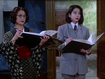 Movie still from “The Pillow Book” (1995), directed by Peter Greenaway – Two women are holding open books in their hands; Medium shot, Low angle