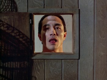Movie still from “The Pillow Book” (1995), directed by Peter Greenaway – A man looking into a mirror in a wooden frame; Close Up shot, Low angle