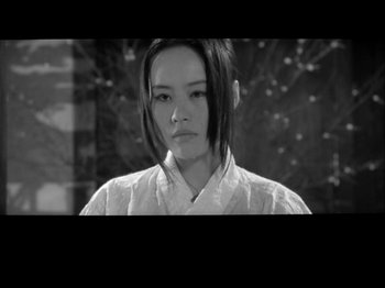 Movie still from “The Pillow Book” (1995), directed by Peter Greenaway – A woman in a white shirt and a black robe; Close Up shot, High angle