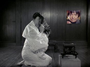 Movie still from “The Pillow Book” (1995), directed by Peter Greenaway – A woman kneeling on the ground holding a bouquet of flowers in front of her face; Medium shot, High angle