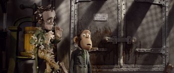 Movie still from “The Pirates! Band of Misfits” (2012), directed by Jeff Newitt – A toy monkey standing in front of a metal door; Medium shot, Low angle