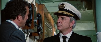 Movie still from “The Poseidon Adventure” (1972), directed by Ronald Neame – A man wearing a hat standing in front of a phone booth; Close Up shot, Low angle