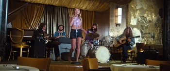 Movie still from “The Poseidon Adventure” (1972), directed by Ronald Neame – A woman singing into a microphone on a stage; Wide shot, Low angle