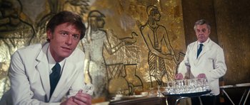 Movie still from “The Poseidon Adventure” (1972), directed by Ronald Neame – A man sitting in front of a painting of a man and a woman; Medium shot, Over the shoulder angle