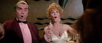 Movie still from “The Poseidon Adventure” (1972), directed by Ronald Neame – A woman in a white dress is sitting at a table; Close Up shot, Low angle