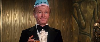 Movie still from “The Poseidon Adventure” (1972), directed by Ronald Neame – A man in a suit and a hat is holding a glass of wine; Close Up shot, Low angle
