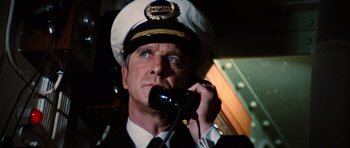 Movie still from “The Poseidon Adventure” (1972), directed by Ronald Neame – A man wearing a hat talking on a phone; Close Up shot, Low angle