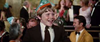 Movie still from “The Poseidon Adventure” (1972), directed by Ronald Neame – A young boy wearing a suit and tie and a party hat; Close Up shot, Over the shoulder angle