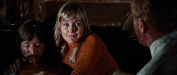 Movie still from “The Poseidon Adventure” (1972), directed by Ronald Neame – A young woman in a orange shirt is sitting on a couch; Close Up shot, Low angle