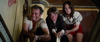 Movie still from “The Poseidon Adventure” (1972), directed by Ronald Neame – A man and two women and a boy playing a video game; Medium shot, High angle