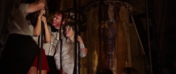 Movie still from “The Poseidon Adventure” (1972), directed by Ronald Neame – A man standing next to a woman holding a remote control; Medium shot, Low angle