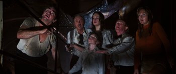 Movie still from “The Poseidon Adventure” (1972), directed by Ronald Neame – A group of people standing next to each other in a dark room; Medium shot, Low angle