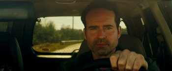 Movie still from “The Prince” (2014), directed by Brian A. Miller – A person in a car holding a steering wheel; Close Up shot, Low angle