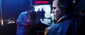 Movie still from “The Prince” (2014), directed by Brian A. Miller – A man standing in front of a group of people in a room; Close Up shot, Over the shoulder angle