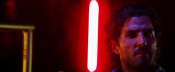 Movie still from “The Prince” (2014), directed by Brian A. Miller – A man with long curly hair is holding a light saber in his hand; Close Up shot, Low angle