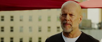 Movie still from “The Prince” (2014), directed by Brian A. Miller – An older man with a shaved head is looking at the camera; Close Up shot, Low angle