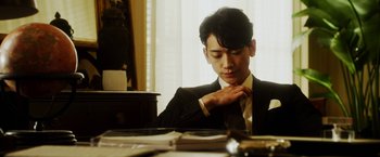 Movie still from “The Prince” (2014), directed by Brian A. Miller – A man in a suit and tie sitting at a table; Close Up shot, Low angle