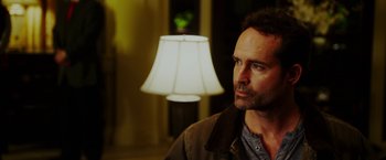 Movie still from “The Prince” (2014), directed by Brian A. Miller – A person in a room near a lamp; Close Up shot, Over the shoulder angle