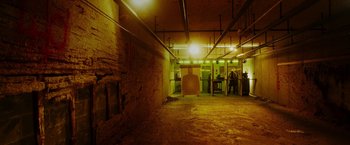 Movie still from “The Prince” (2014), directed by Brian A. Miller – An indoor shooting range filled with guns and people; Extreme Wide shot, High angle