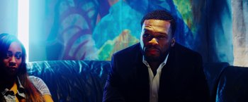 Movie still from “The Prince” (2014), directed by Brian A. Miller – A person wearing a suit and tie; Close Up shot, Over the shoulder angle