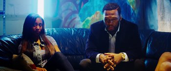 Movie still from “The Prince” (2014), directed by Brian A. Miller – A man and a woman sitting on a couch talking; Medium shot, Over the shoulder angle