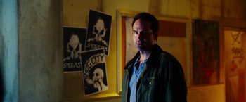 Movie still from “The Prince” (2014), directed by Brian A. Miller – A man standing in front of a bunch of posters; Medium shot, Over the shoulder angle