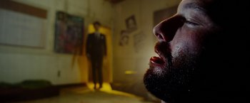 Movie still from “The Prince” (2014), directed by Brian A. Miller – A man with a goatee and a suit in a room; Close Up shot, Low angle