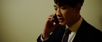 Movie still from “The Prince” (2014), directed by Brian A. Miller – A man in a suit talking on a cell phone; Close Up shot, Low angle