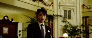 Movie still from “The Prince” (2014), directed by Brian A. Miller – A man in a suit and tie standing next to a fireplace; Close Up shot, Low angle