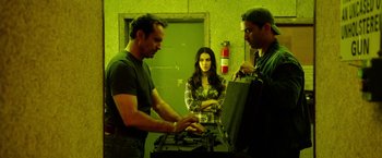 Movie still from “The Prince” (2014), directed by Brian A. Miller – A man and a woman standing in front of a man holding a briefcase; Medium shot, Low angle