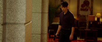 Movie still from “The Prince” (2014), directed by Brian A. Miller – A young man holding a gun in his hand; Medium shot, Over the shoulder angle