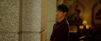 Movie still from “The Prince” (2014), directed by Brian A. Miller – A young man standing next to a stone wall; Medium shot, Over the shoulder angle