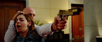 Movie still from “The Prince” (2014), directed by Brian A. Miller – A man with long hair is holding a gun in his hand; Medium shot, Over the shoulder angle