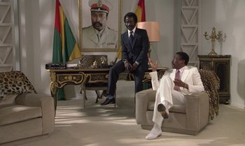 Movie still from “The Professional” (1981), directed by Georges Lautner – Two men in suits sitting in a living room; Wide shot, Low angle